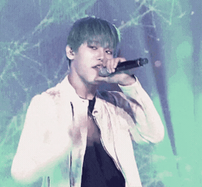 A Young Man With Green Hair Is Singing Into A Microphone While Wearing A White Jacket GIF