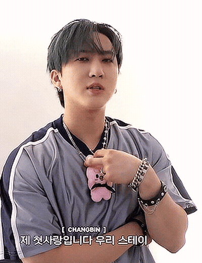 A Young Man With Green Hair Is Wearing A Necklace And Bracelets While Holding A Stuffed Animal . GIF