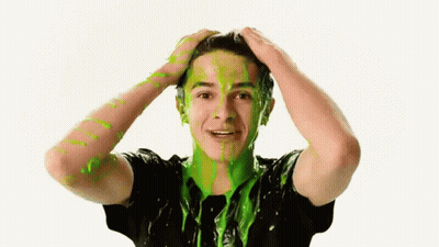 A Young Man With Green Slime On His Face Is Holding His Head GIF