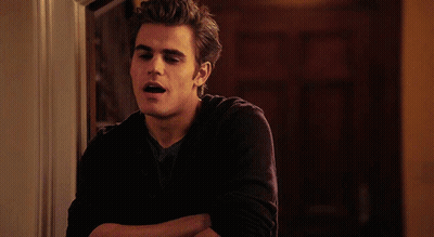 A Young Man With His Arms Crossed Is Leaning Against A Wall GIF
