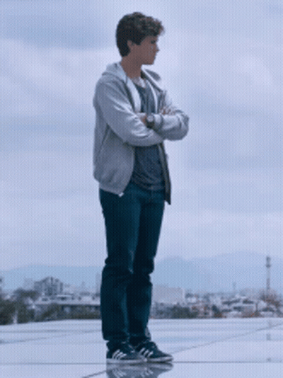 A Young Man With His Arms Crossed Stands On A Rooftop GIF