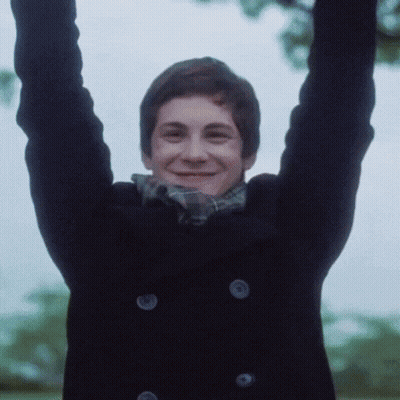 A Young Man With His Arms In The Air Is Wearing A Black Coat GIF