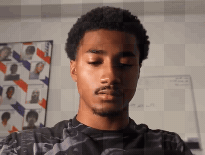 A Young Man With His Eyes Closed Is Standing In Front Of A White Board With A Picture Of A Man On It GIF