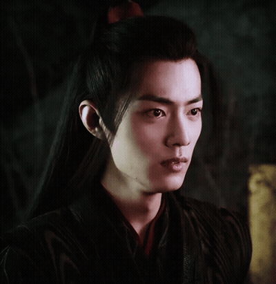 A Young Man With Long Black Hair And A Red Bow In His Hair GIF