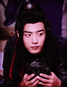 A Young Man With Long Black Hair Is Holding A Fan In His Hands GIF