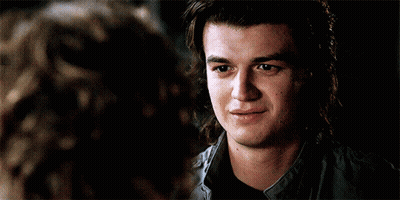 A Young Man With Long Hair Is Smiling While Looking At A Woman . GIF