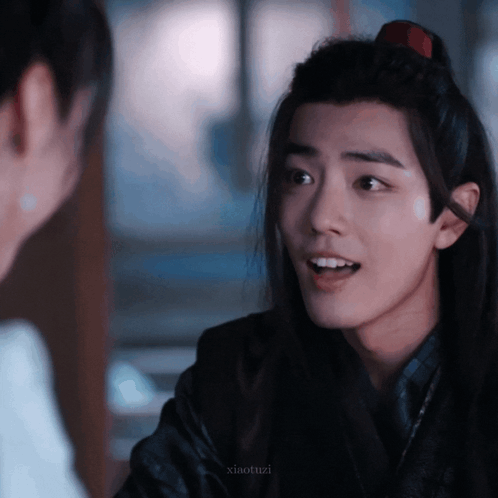 A Young Man With Long Hair Is Talking To Another Man GIF