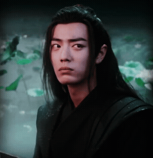 A Young Man With Long Hair Looks At The Camera GIF