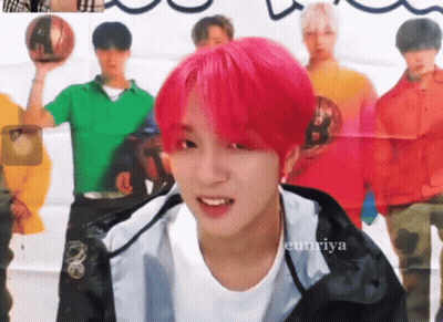 A Young Man With Pink Hair Is Smiling In Front Of A Group Of Men GIF