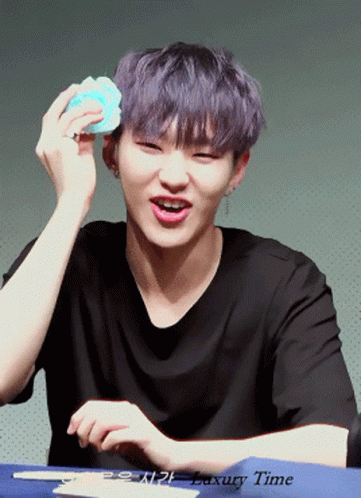 A Young Man With Purple Hair Is Holding A Blue Object In Front Of His Face And The Words Luxury Time Are Below Him GIF