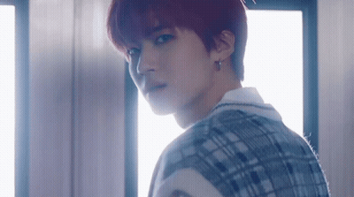 A Young Man With Red Hair And A Plaid Vest Is Standing In Front Of A Window . GIF