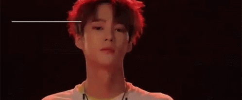 A Young Man With Red Hair Is Standing In Front Of A Black Background And The Name Ayno Is Written Above Him . GIF