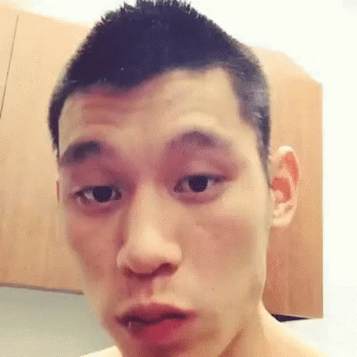 A Young Man With Short Hair Is Making A Funny Face In Front Of A Wooden Cabinet . GIF