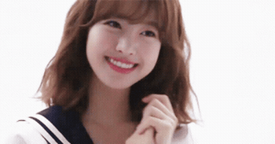 A Young Woman In A Sailor Suit Is Smiling And Holding Her Hands Together . GIF