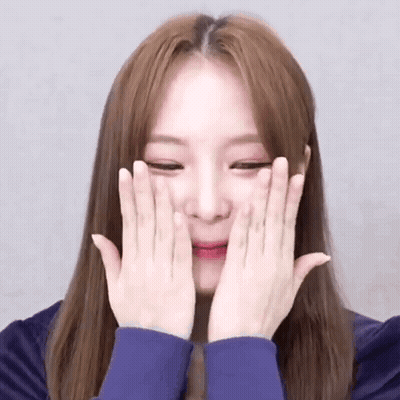 A Young Woman Is Covering Her Face With Her Hands . GIF