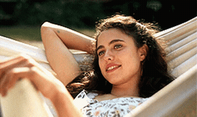 A Young Woman Is Laying In A Hammock With Her Head Resting On Her Arm GIF