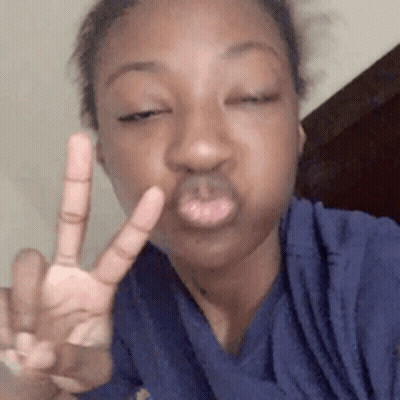 A Young Woman Is Making A Peace Sign With Her Hand . GIF