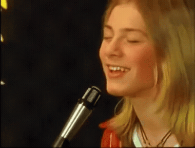 A Young Woman Is Singing Into A Microphone With Her Eyes Closed . GIF