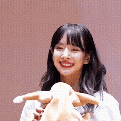 A Young Woman Is Smiling While Holding A Stuffed Animal . GIF