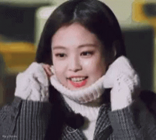 A Young Woman Wearing A Turtleneck Sweater And Gloves Is Smiling . GIF