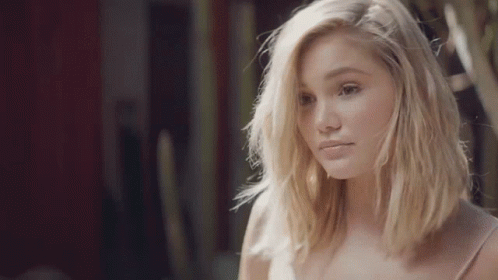 A Young Woman With Blonde Hair Is Looking At The Camera . GIF