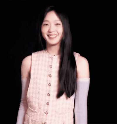 A Young Woman With Long Black Hair Is Wearing A Pink Dress And Purple Gloves And Smiling . GIF