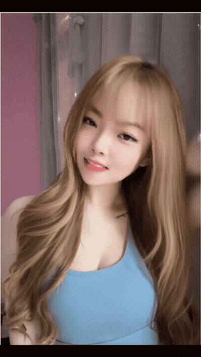 A Young Woman With Long Blonde Hair Is Wearing A Blue Tank Top GIF