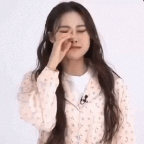 A Young Woman With Long Hair Is Covering Her Nose With Her Hand . GIF
