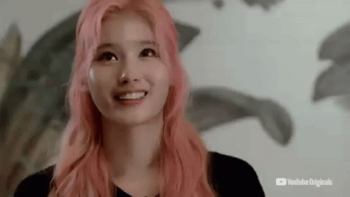 A Young Woman With Pink Hair Is Smiling And Looking Up . GIF