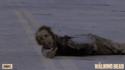 A Zombie Is Laying On The Ground With A Walking Dead Logo In The Background GIF