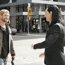Actors Chris Hemsworth And Tom Hiddleston Hand Signs GIF