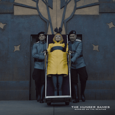 An Ad For The Hunger Games Shows A Woman In A Yellow Coat GIF