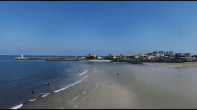 An Aerial View Of A Beach With Buildings In The Distance GIF