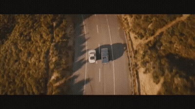 An Aerial View Of A Car Driving Down A Road . GIF