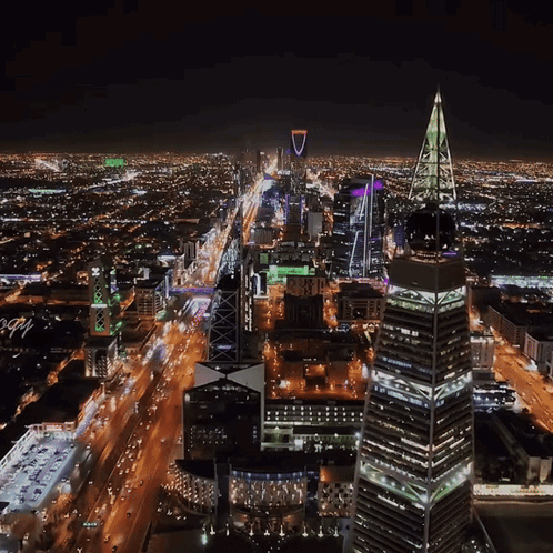 An Aerial View Of A City At Night With A Tall Building In The Middle That Says ' Lbc ' On It GIF