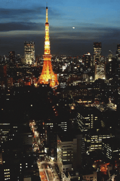 An Aerial View Of A City At Night With A Tower In The Foreground GIF