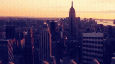 An Aerial View Of A City Skyline At Sunset With The Empire State Building In The Foreground GIF