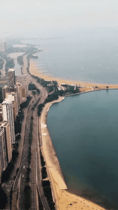 An Aerial View Of A City With A Beach And A Lake GIF