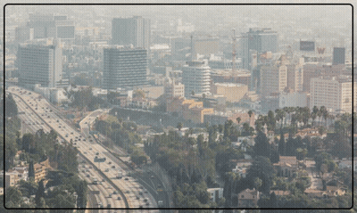 An Aerial View Of A City With A Highway In The Foreground And A Few Buildings In The Background GIF