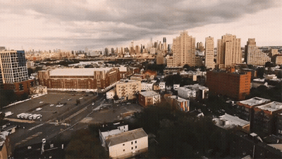 An Aerial View Of A City With A Lot Of Buildings And A Stadium In The Background GIF