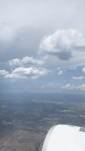 An Aerial View Of A Cloudy Sky With A Wing Of An Airplane In The Foreground GIF