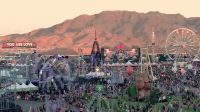 An Aerial View Of A Festival With Mountains In The Background And A Sign That Says You Are Love GIF