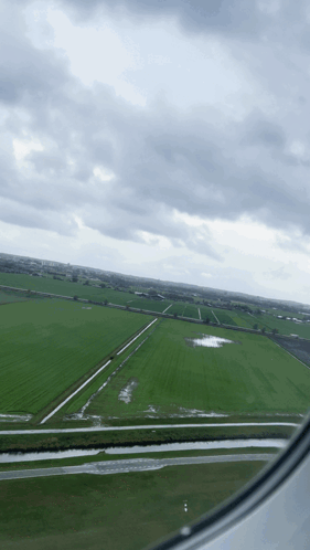 An Aerial View Of A Green Field With A Cloudy Sky GIF