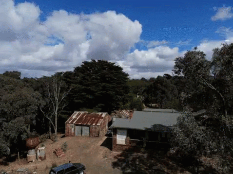 An Aerial View Of A House Surrounded By Trees And Bushes GIF
