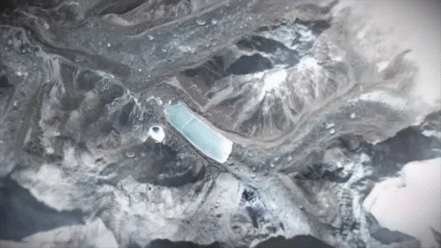 An Aerial View Of A Mountain Range With A Blue Object In The Middle GIF