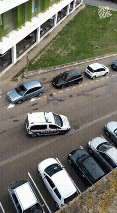An Aerial View Of A Parking Lot With A Police Car In The Foreground GIF