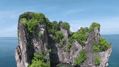 An Aerial View Of A Rocky Island In The Middle Of The Ocean . GIF