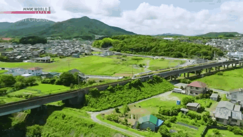 An Aerial View Of A Train Going Over A Bridge With Nhk World Written On The Bottom GIF
