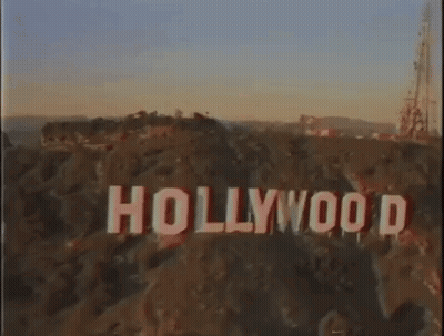 An Aerial View Of The Hollywood Sign On Top Of A Hill At Sunset . GIF