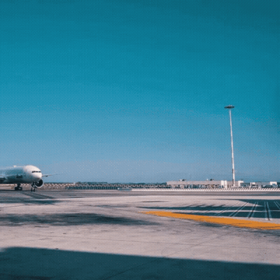 An Airplane Is Parked On A Runway With A Building In The Background That Says Airways GIF